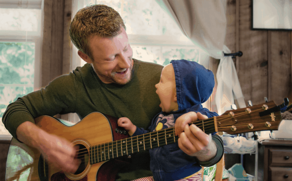 Dad playing the guitar to his baby