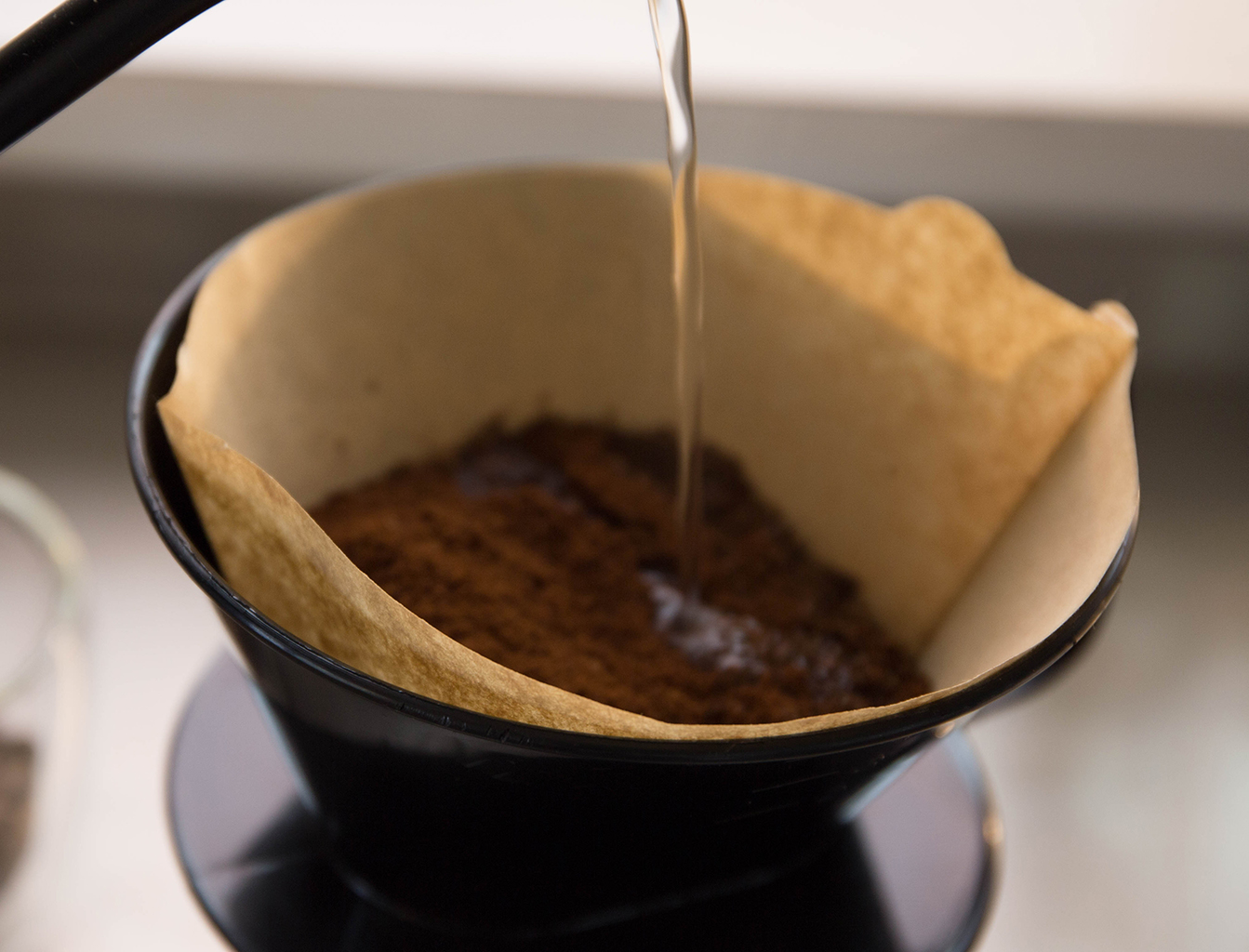 Making filtered coffee, pouring hot water through a coffee filter