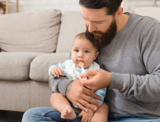 Father feeding his cute baby son at home